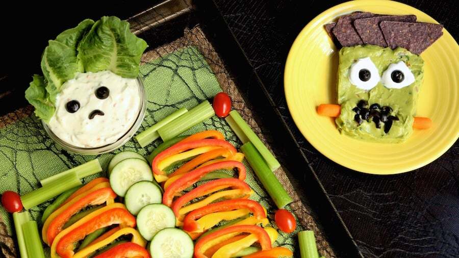 tray with vegetables shaped like a skeleton alongside a guacamole decoration looking like Frankenstein's monster