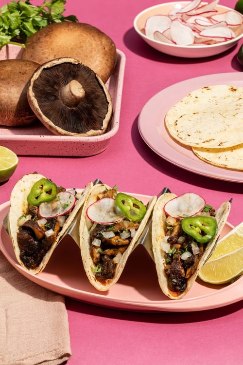 3 Tacos filled with mushrooms, radish and topped with jalapeno, lime and tortillas on side