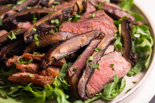 Strip steak with portabella mushrooms on a bed of greens
